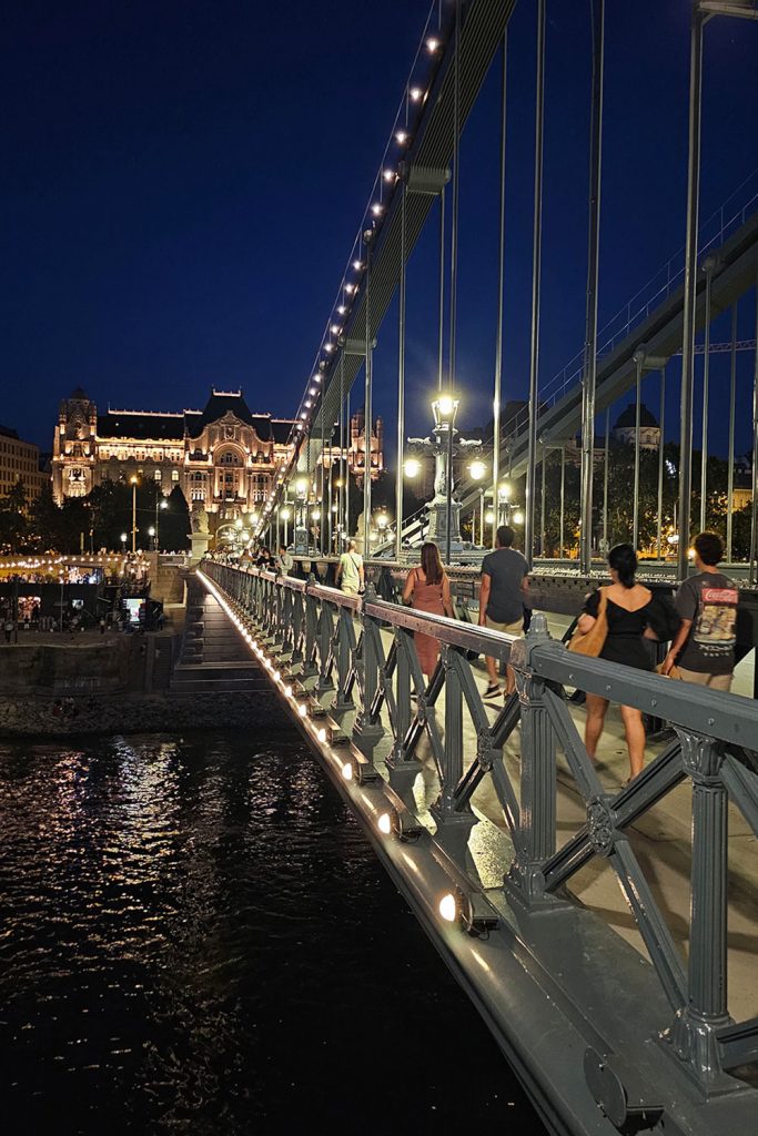 people walking over Chain Bridge in Budapest in the evening