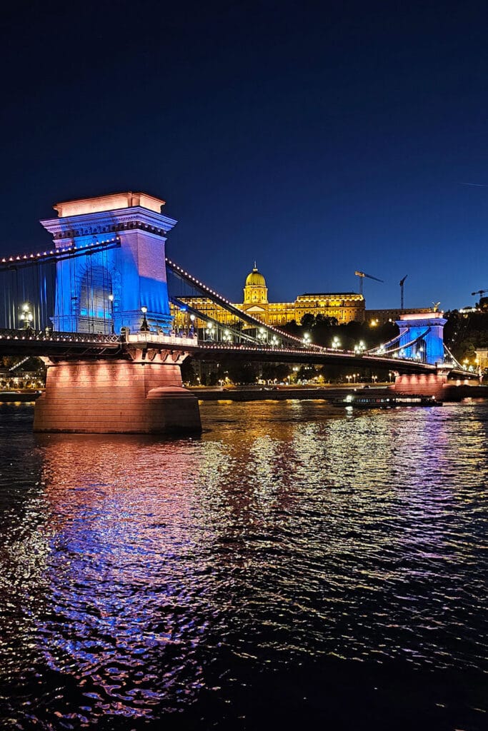 Budapest Chain Bridge illuminated in blue and lilac colors
