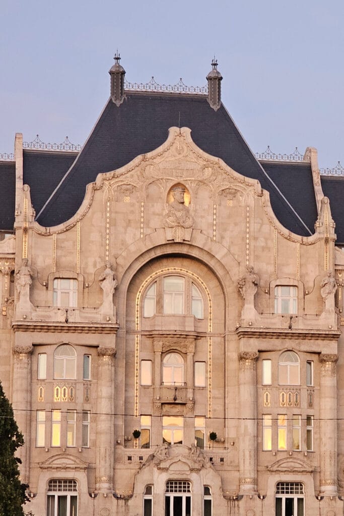 the façade of Four Seasons Gresham Palace with shining golden details at sunset